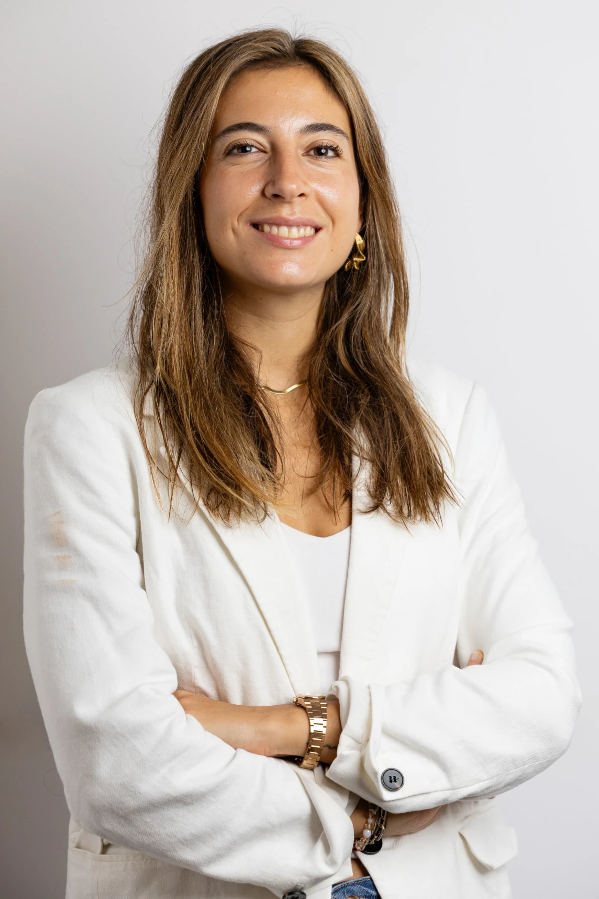Olga de Andrés sonriendo con americana blanca y los brazos cruzados